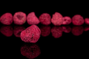 Lot of whole dried raspberry one in front isolated on black glass