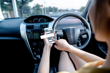 Young woman typing text on mobile smartphone.while driving a car