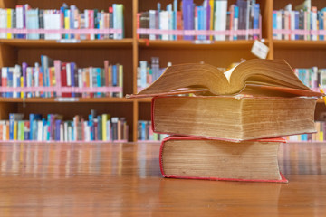 Books stack on table with book shelf background in library room education zone, education and knowledge concept.