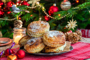 Obraz na płótnie Canvas Homemade Christmas puff pastry mince pies with Christmas tree in the background
