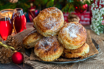 Homemade Christmas puff pastry mince pies with Christmas tree in the background
