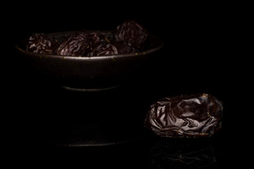 Lot of whole dried brown date fruit in glazed bowl isolated on black glass