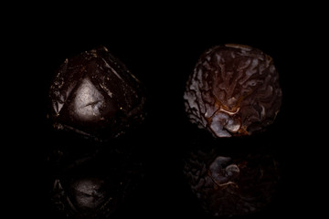 Group of two whole dried brown date fruit isolated on black glass