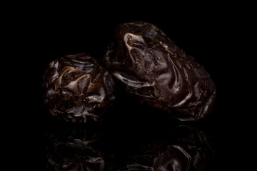 Group of two whole dried brown date fruit isolated on black glass