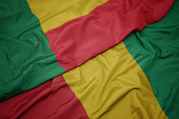 waving colorful flag of guinea and national flag of benin.