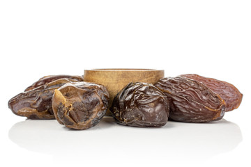 Group of five whole dried brown date fruit around bowl isolated on white background