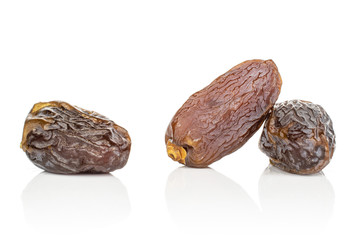 Group of three whole dried brown date fruit isolated on white background