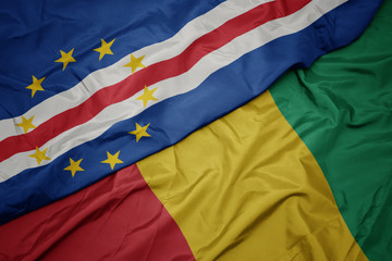 waving colorful flag of guinea and national flag of cape verde.