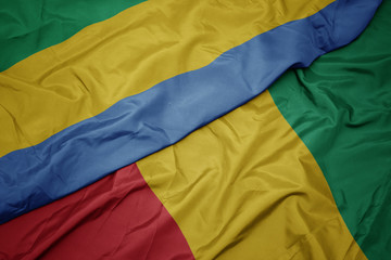 waving colorful flag of guinea and national flag of gabon.