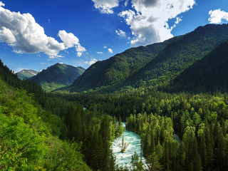 Colorful landscape with high mountains, beautiful curved river, green forest, blue sky with clouds of sunlight. Mountain valley for traveling.