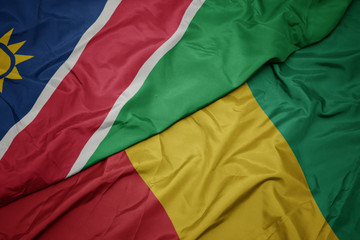 waving colorful flag of guinea and national flag of namibia.