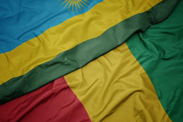 waving colorful flag of guinea and national flag of rwanda.