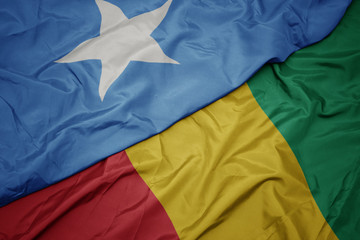 waving colorful flag of guinea and national flag of somalia.