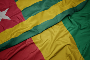 waving colorful flag of guinea and national flag of togo.