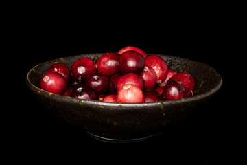 Lot of whole fresh red cranberry in glazed bowl isolated on black glass