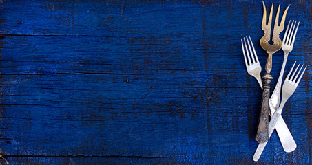 Vintage cutlery - spoons, forks and knives on an old wooden background.