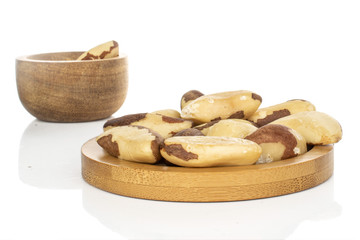 Lot of whole unshelled brazil brown nut in bamboo bowl on round bamboo coaster isolated on white background