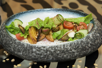 Salad with fried potato lettuce pickled cucumbers and tomatoes on decorate plate