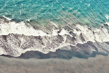 Atlantic in bright blue-green color with a small part of lava sand beach on Tenerife