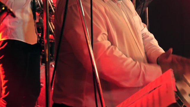 Saxophonist and Bongo drum percussionist performs on stage filled with red light
