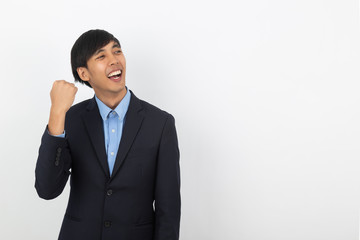 Excited young business Asian man raising his fists with happy delighted face, celebrating success isolated on white background.
