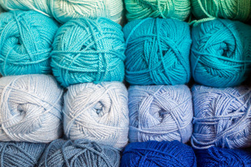 A full frame photograph of balls of wool stacked on a shelf