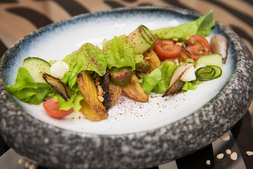 Salad with fried potato lettuce pickled cucumbers and tomatoes on decorate plate