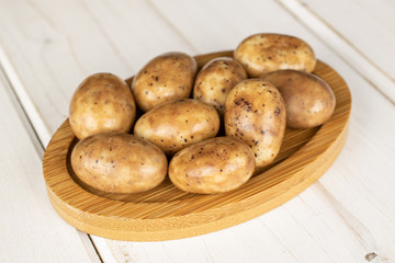 Lot of whole sweet tiramisu brown almond nut on round bamboo coaster on white wood