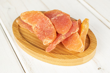 Lot of whole dried orange papaya piece on round bamboo coaster on white wood