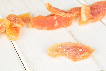 Lot of whole dried orange papaya piece on white wood