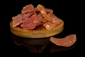 Lot of whole dried orange papaya piece on round bamboo coaster isolated on black glass