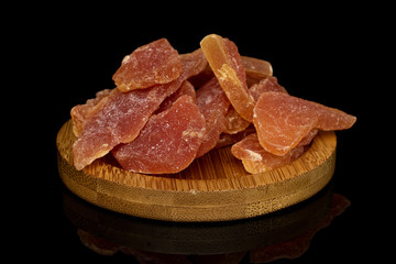 Lot of whole dried orange papaya piece on round bamboo coaster isolated on black glass