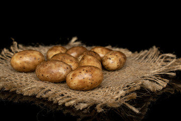 Lot of whole tiramisu brown almond nut with jute fabric isolated on black glass