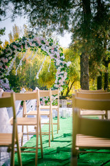 Wedding ceremony. Floral wedding decor in the park. American wedding. Chairs, arch and flowers for a wedding ceremony in a park