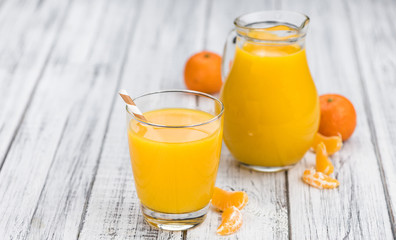 Wooden table with fresh made Tangerine Juice (close-up shot)