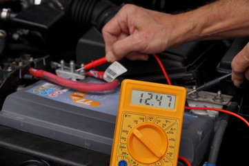 Car repair shop. Battery voltage measurement with a meter.