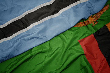 waving colorful flag of zambia and national flag of botswana.