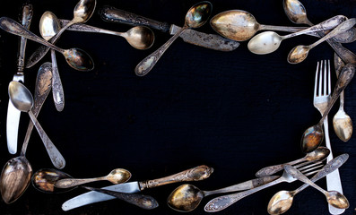 Vintage cutlery - spoons, forks and knives on an old wooden background.