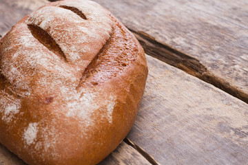 Whole loaf of a crispy bread on wooden background. Loaf of fresh bread on wooden boards. Space for text.