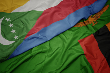 waving colorful flag of zambia and national flag of comoros.