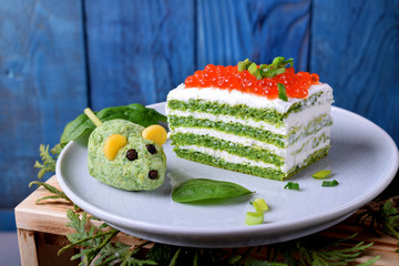 Layered salty cake with spinach, cream cheese and red caviar and a mouse shaped appetizer next to...