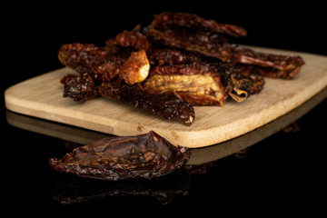 Lot of whole dried red tomato piece on bamboo cutting board isolated on black glass