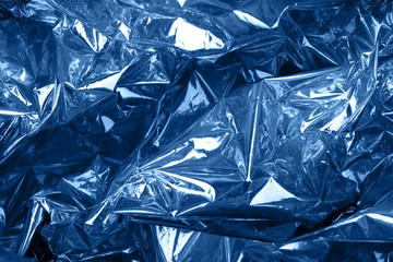 Crumpled silver paper with golographic and chameleon effect toned blue color. © Ira_Shpiller