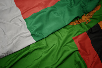 waving colorful flag of zambia and national flag of madagascar.