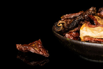 Lot of whole dried red tomato piece in glazed bowl isolated on black glass