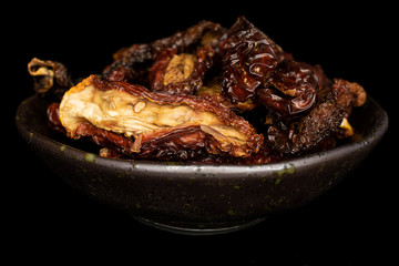 Lot of whole dried red tomato piece in glazed bowl isolated on black glass