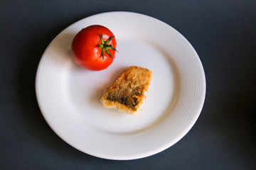  On a plate a slice of fish whole tomatoes
