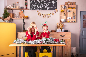 Young attractive smiling woman with her daughter in the kitchen in retro loft style waiting for New Year and Christmas, showing cubes with the inscription 