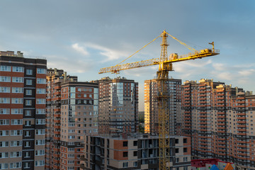 Fototapeta na wymiar Building crane and building under construction against blue sky