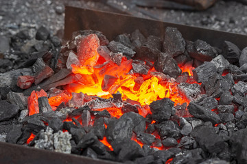 Embers glow in a iron forge. Fire, heat, coal and ash.